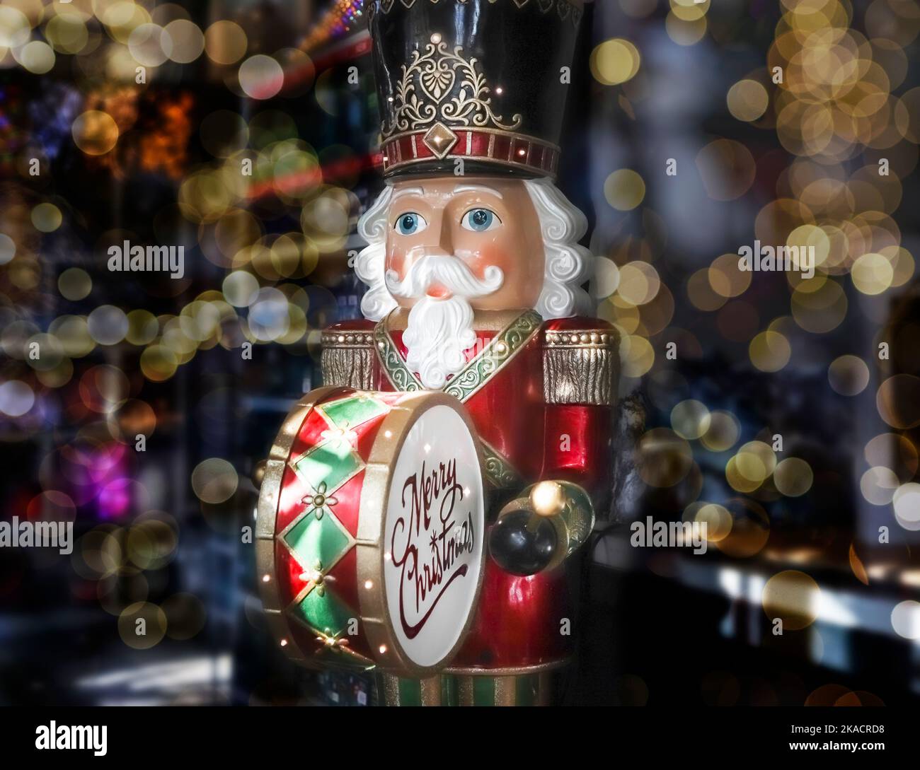 Big nutcracker toy drummer among blurred Christmas lights Stock Photo