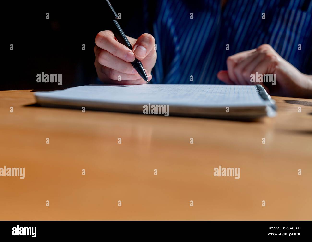 Student hands close up writing with pen in notepad or planner, taking notes on wood office desk with copy space. Stock Photo