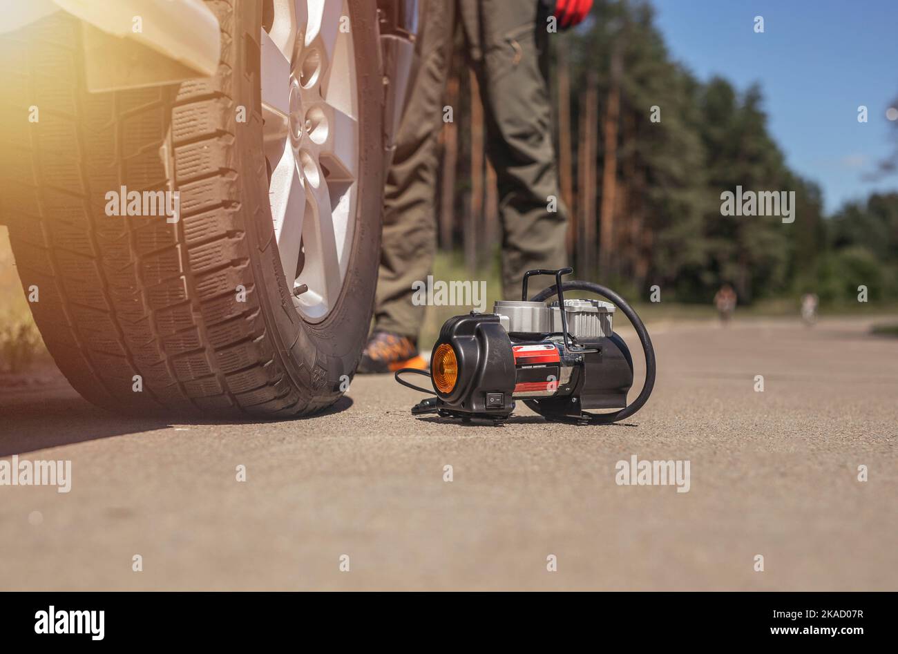 Portable tire pump for inflating car wheel, bottom view. Tyre inflator with manometer on road closeup. Stock Photo