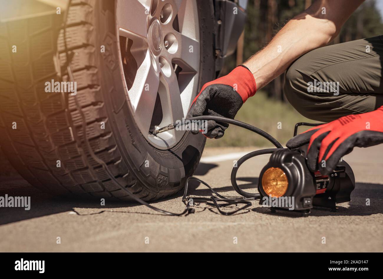 Tire pump inflating car wheel. Tyre inflator in man hands with manometer. Stock Photo
