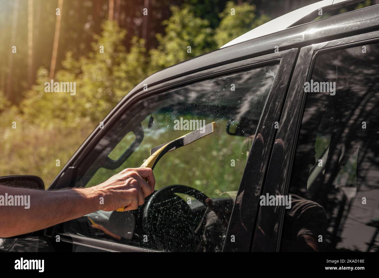 Male hand with car cleaner cleaning auto window in nature. Stock Photo
