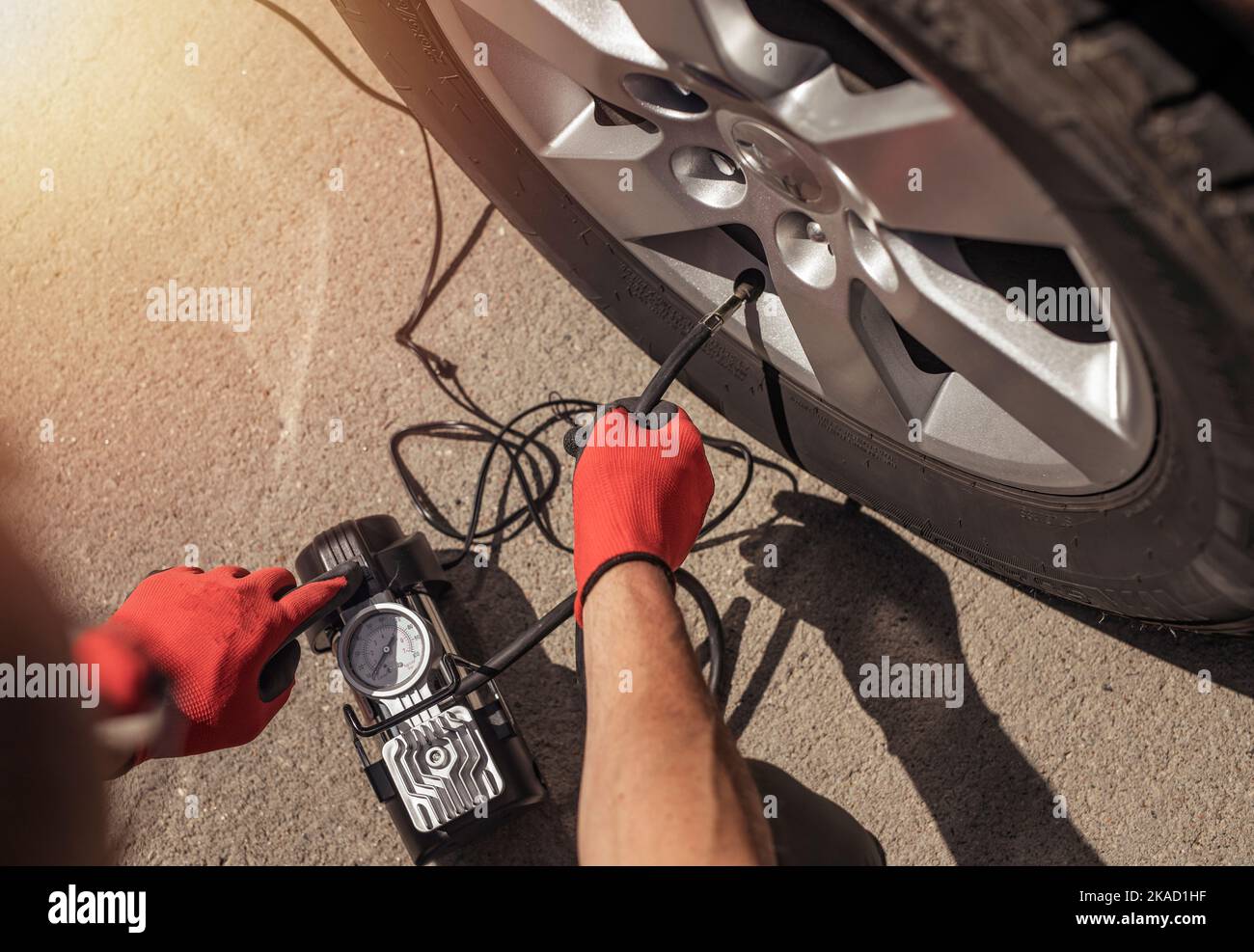 Tire pump inflating car wheel. Tyre inflator in male hands, top view. Stock Photo