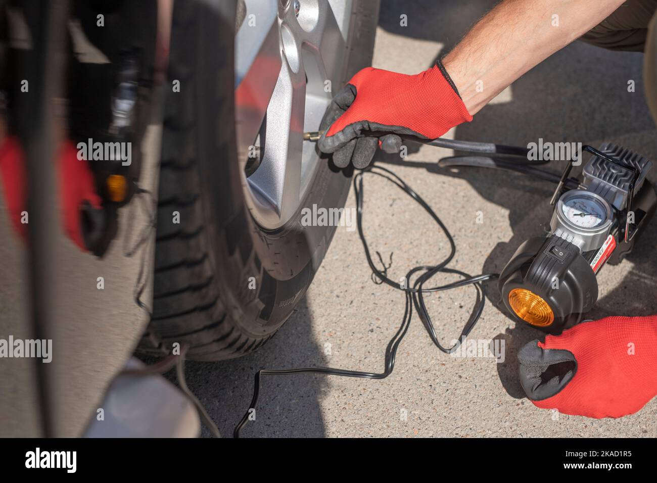 Tire pump inflating car wheel. Tyre inflator in male hands. Stock Photo