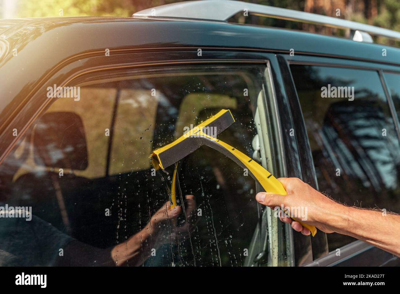 Male hand with car rubber cleaner cleaning and washing automobile side window. Stock Photo