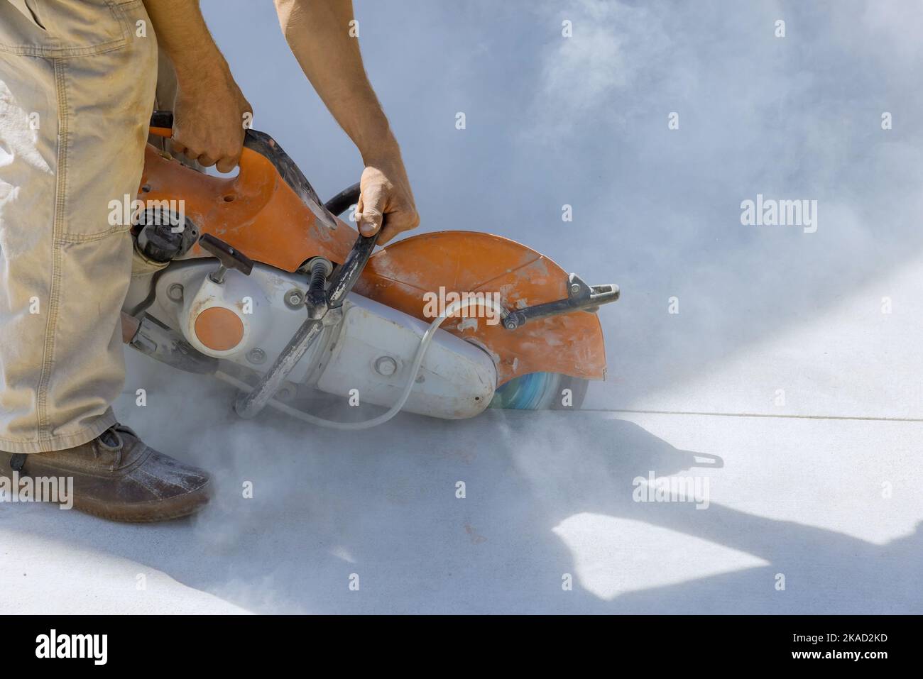 Diamond blade saw used by construction worker to cut concrete sidewalk in reconctruction works Stock Photo