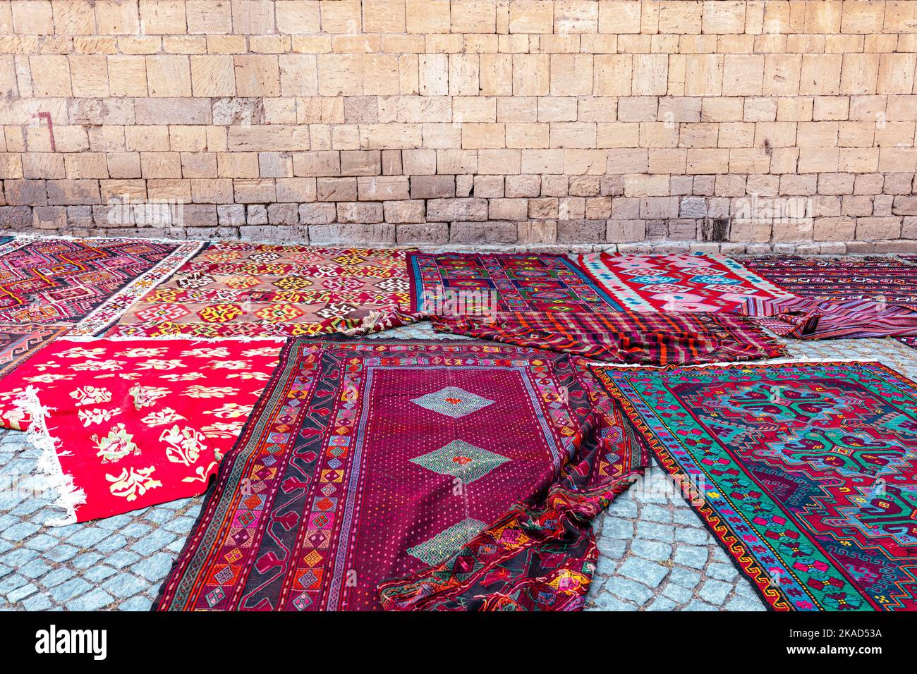 A street market with many colorful carpets lying on a cobbled street in ...