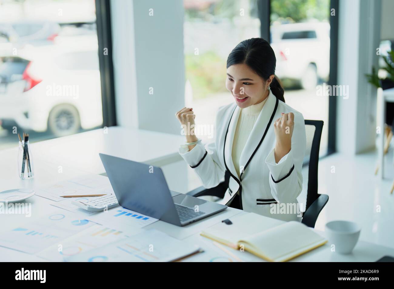 young Asian woman using a computer showing joy at the sales target