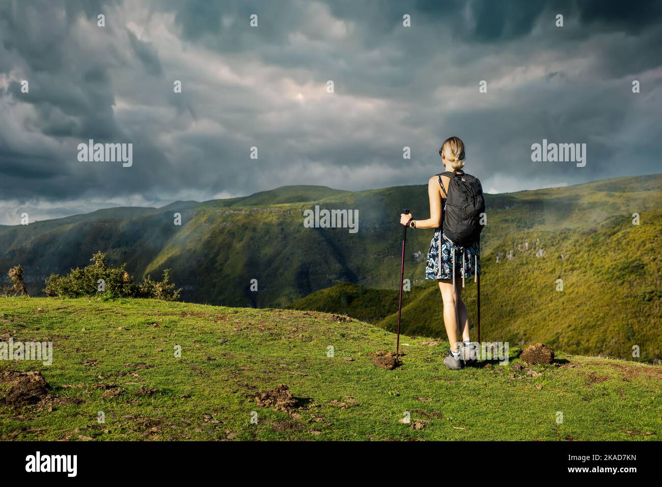 young woman hiking in the mountains. enjoying beautiful lush green landscape view with dramatic sky. copy space Stock Photo