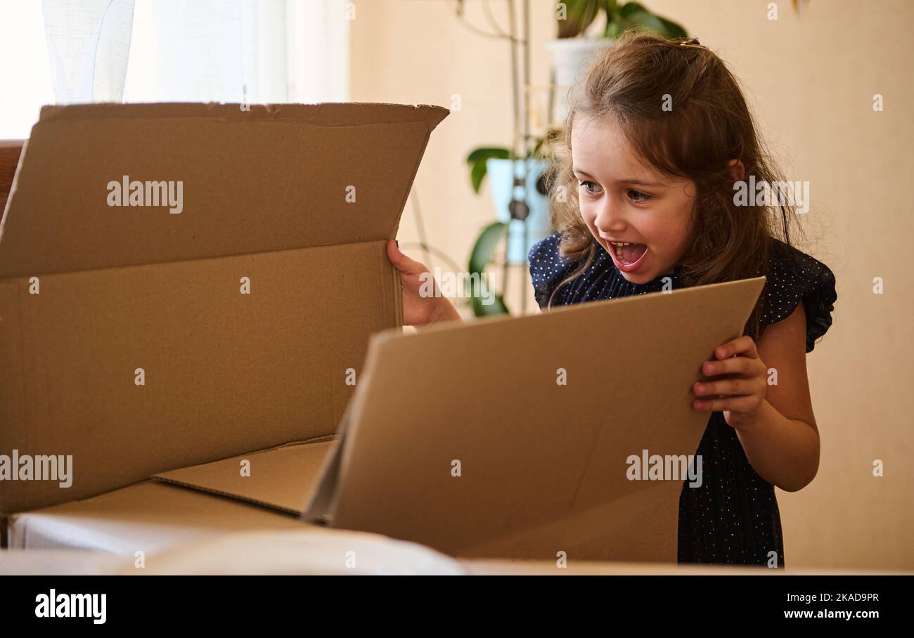 Adorable birthday girl opening the huge gift box with her birthday ...