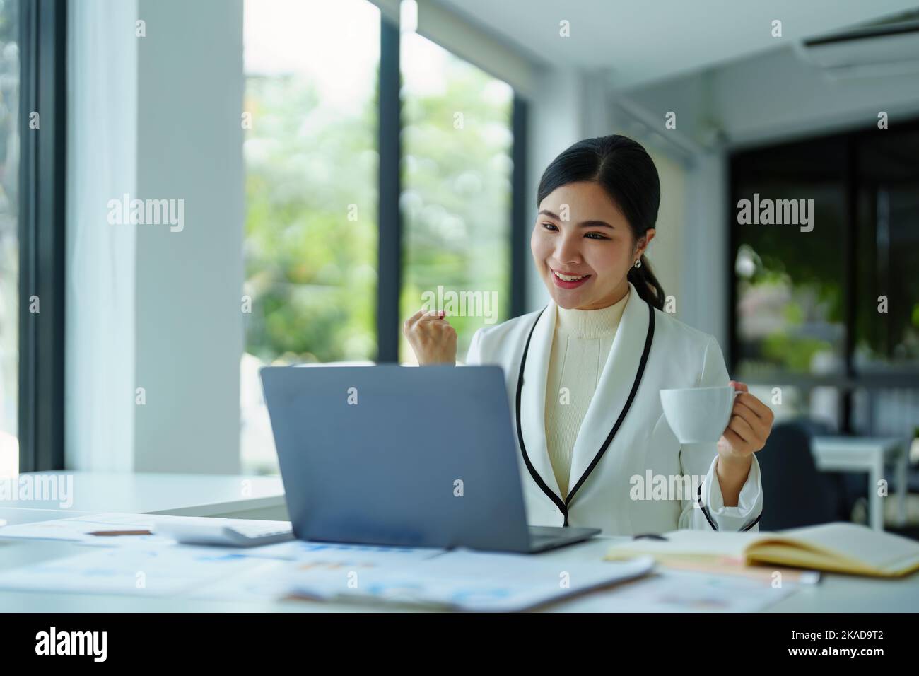young Asian woman using a computer showing joy at the sales target