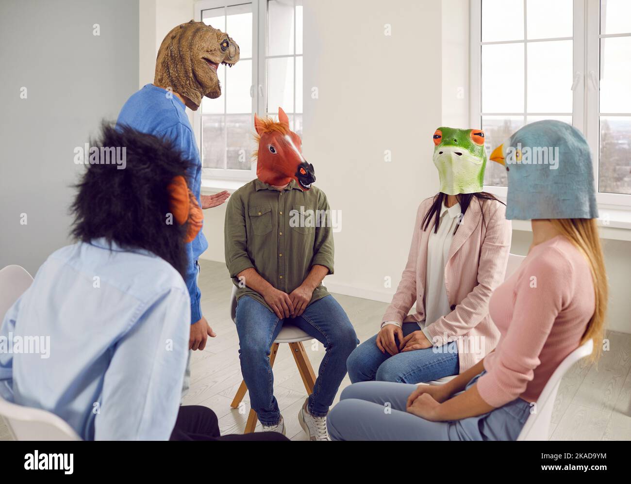 Conversation of young people in rubber masks on their heads during support group meeting. Stock Photo