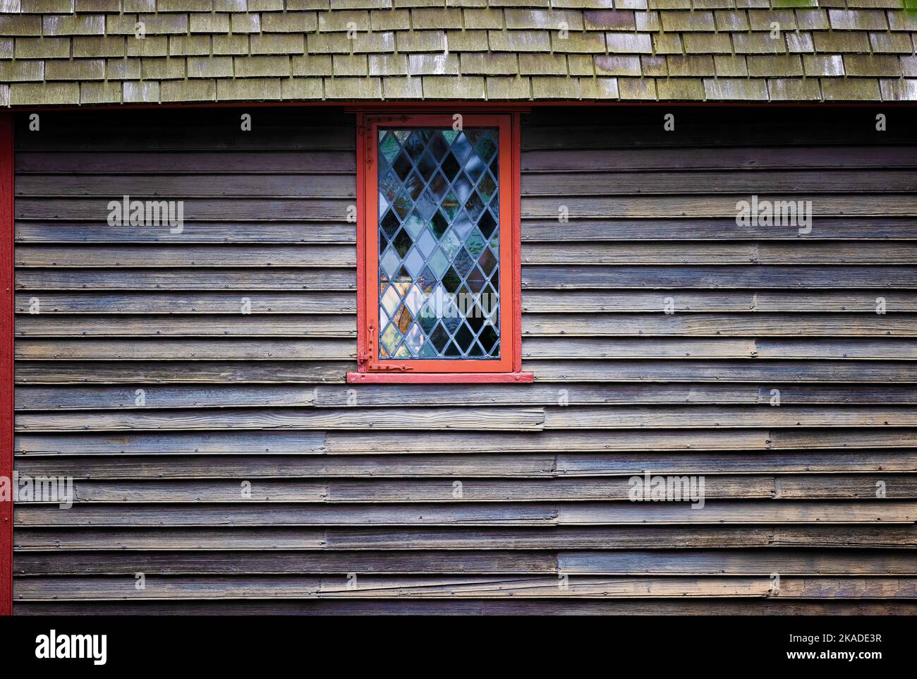 Close up of a diamond shape pane glass window on the outside of a weathered building. Stock Photo