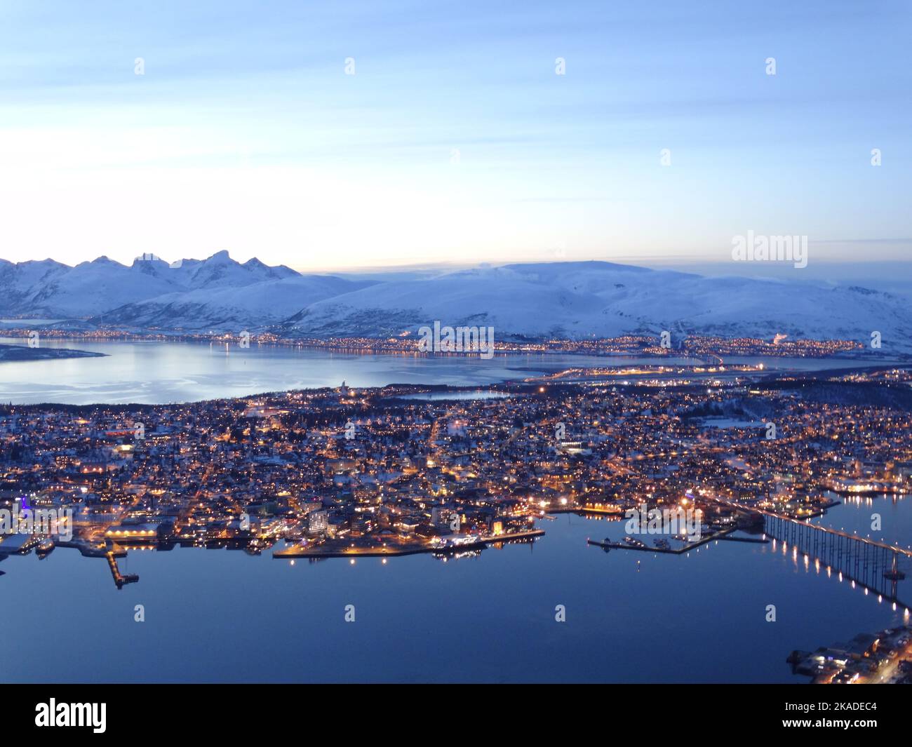 A breathtaking aerial view of the town on the sea with lights and snowy ...