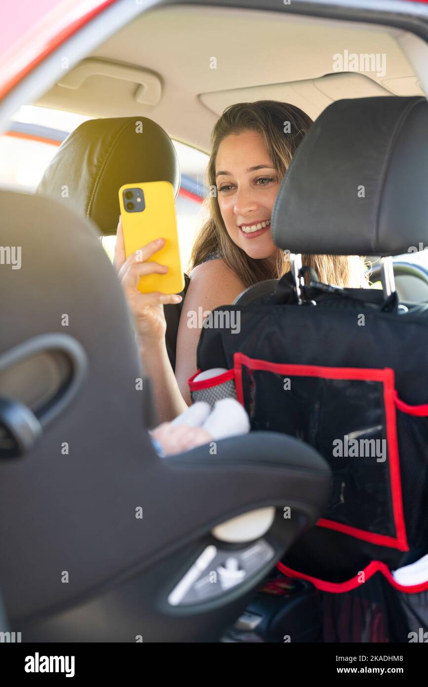Mother taking a picture of her son in the car seat Stock Photo
