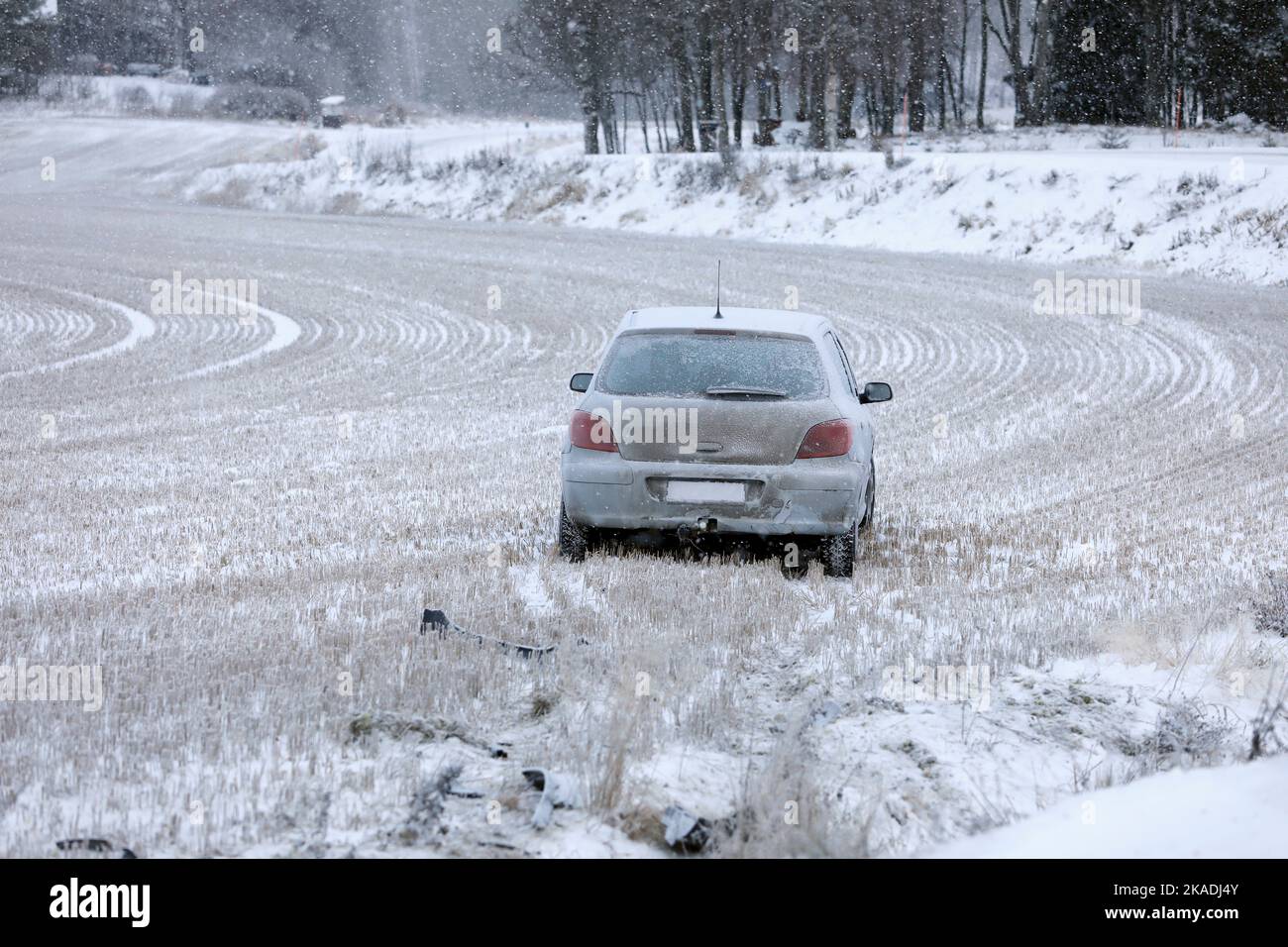 Compact grey car driven off slippery country road in winter and wrecked