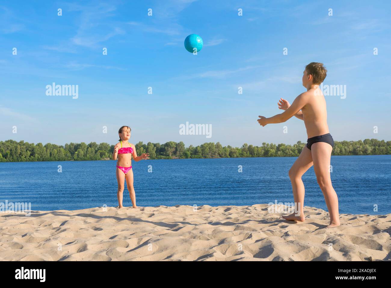 Children play with a ball in the sand on a sunny day. Golden time. Stock Photo