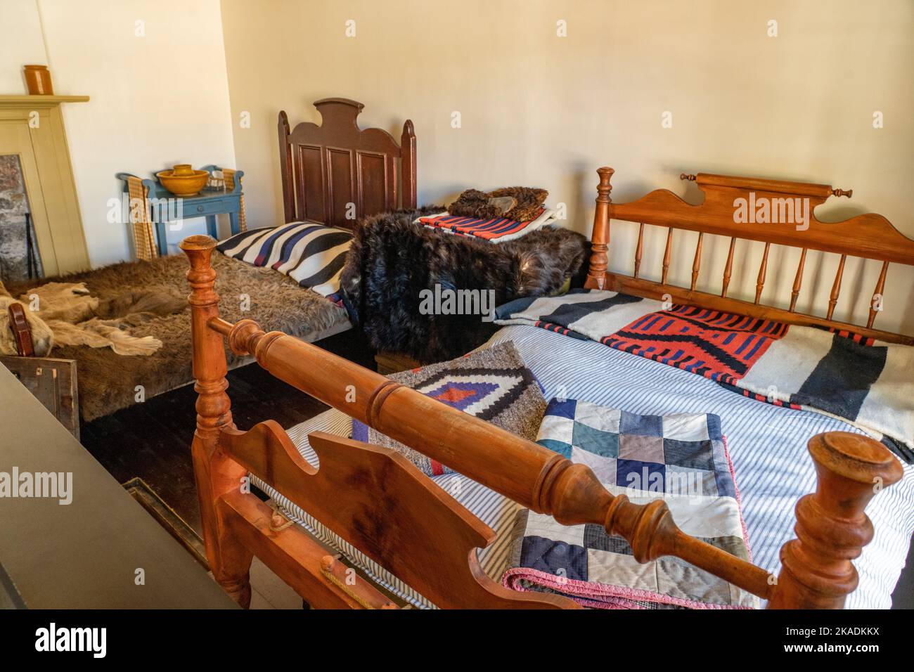 Two antique beds with a quilt & a buffalo hide in a lodging room of the