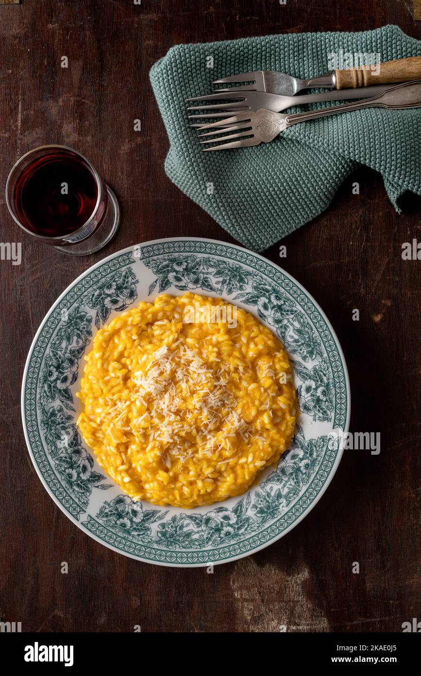 Risotto with pumpkin in a plate on the dark wooden table. Vertical image. Top view. Copy space. Stock Photo