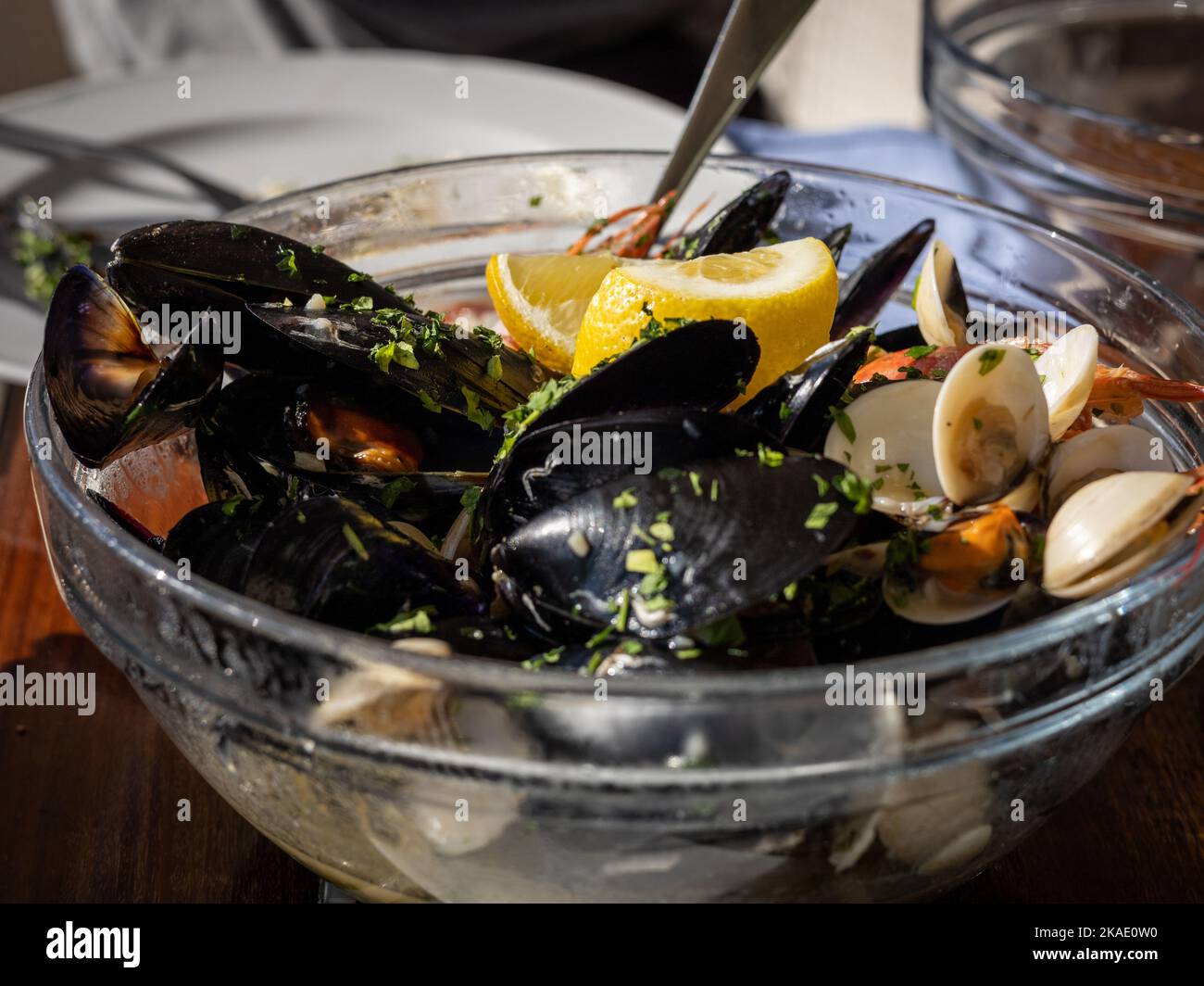 A big glass bowl of mussels, clams and shrimps (seafood, frutti di mare) decorated with lemon, on a restaurant table in Montenegro, Europe. Stock Photo