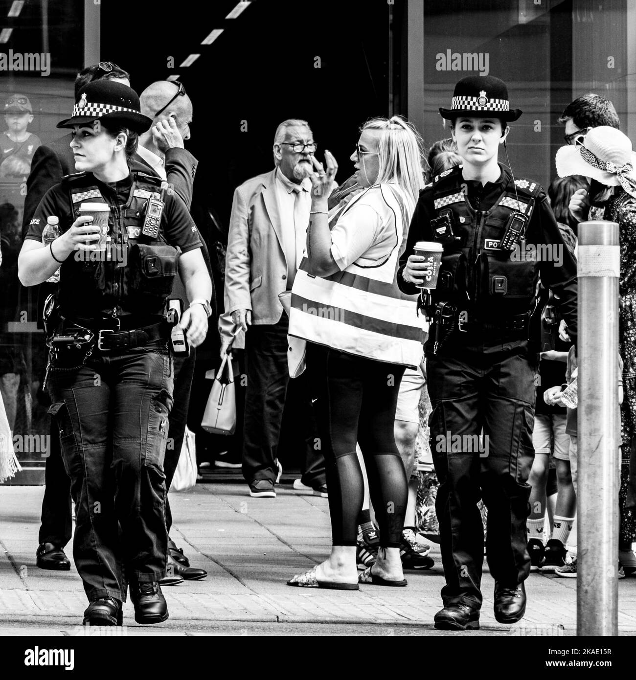 Epsom Surrey, London UK, June 03 2022, Two Women Police Officer Carrying Cups Of Takeaway Coffee On A Crowded Pavement Stock Photo