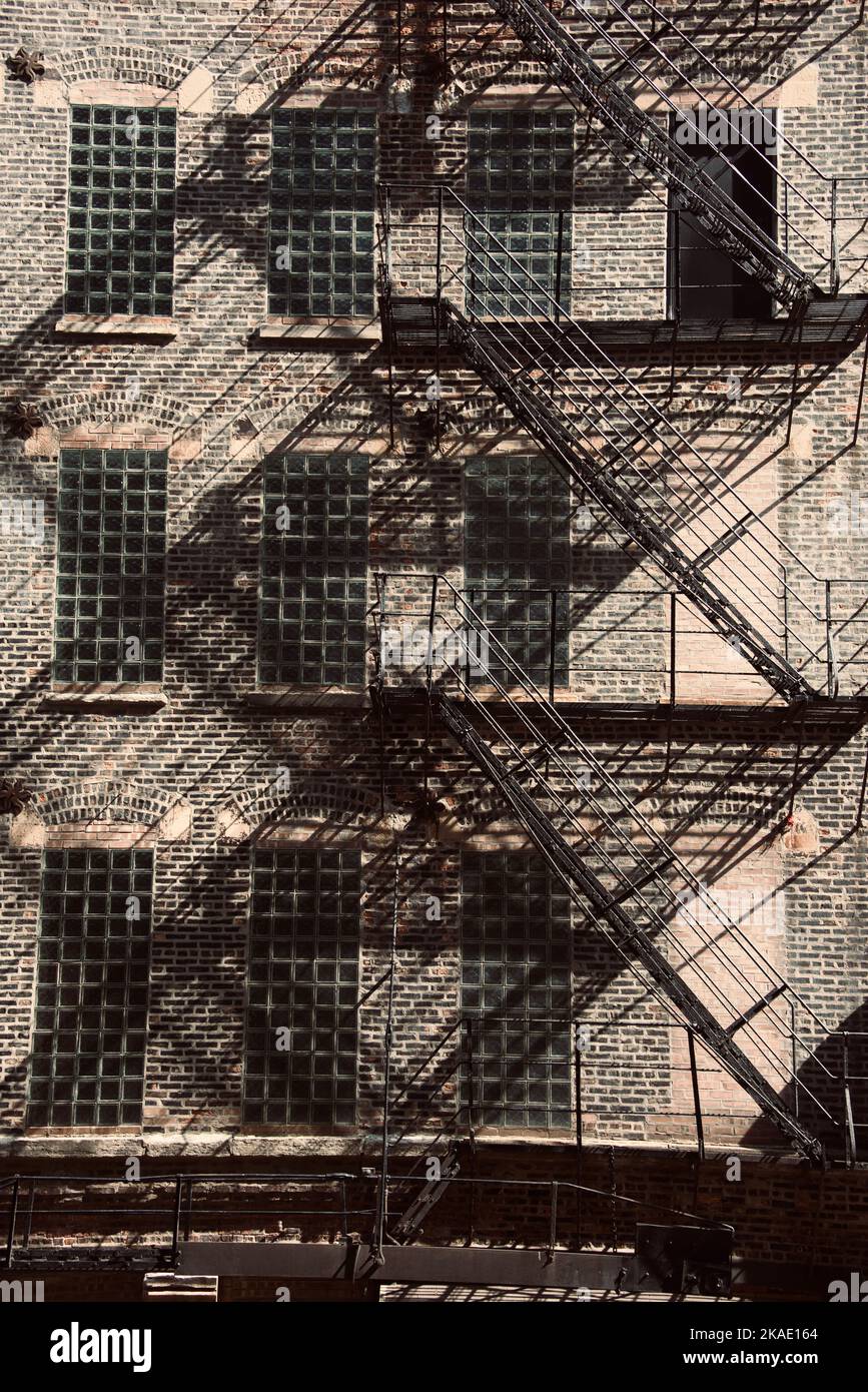 A vertical shot of abstract steel staircase with geometric shape and shadows outside of building Stock Photo