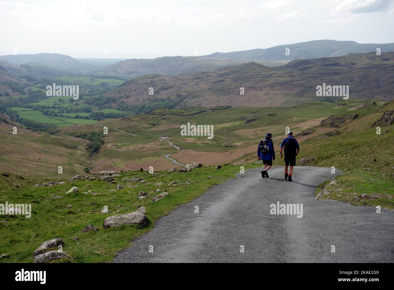 Two Men Walking Down the Hard Knott Pass Road to Eskdale, Lake District National Park, Cumbria, England, UK Stock Photo