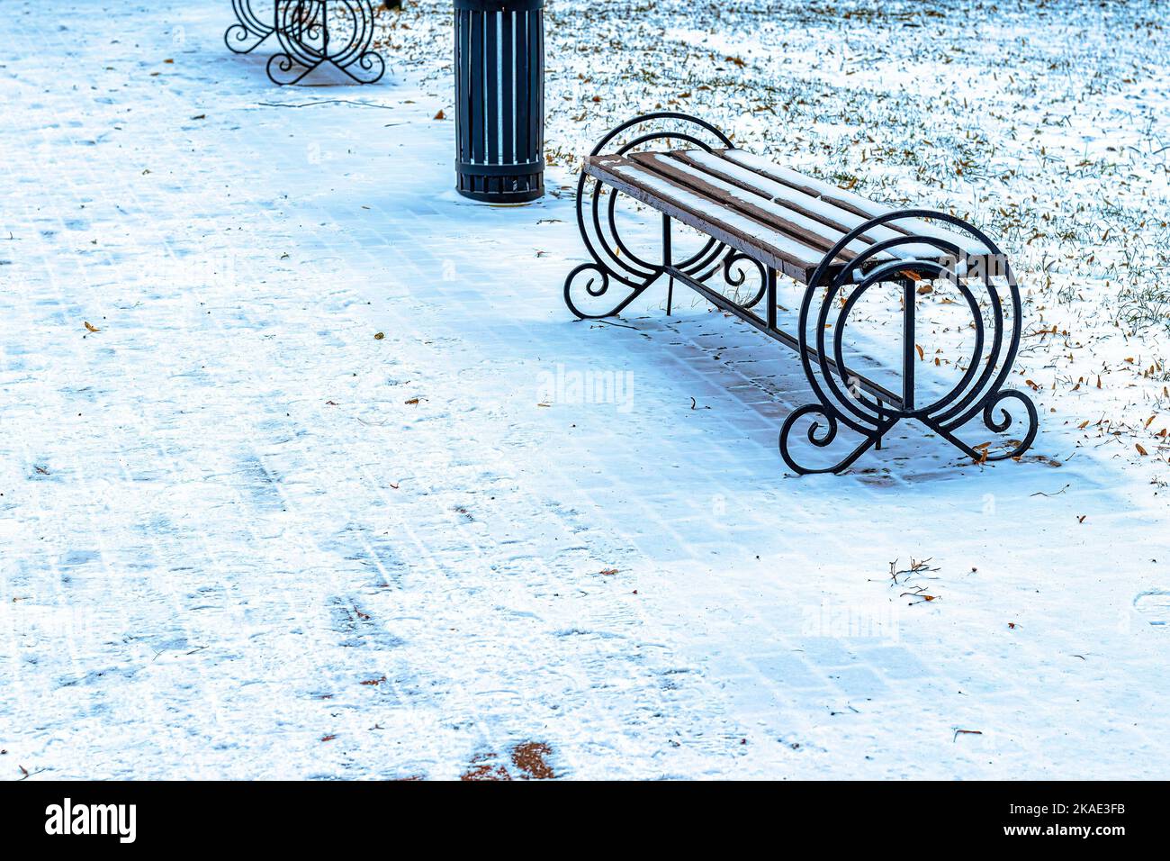 A bench in the park covered with snow in winter. Winter weather and ...
