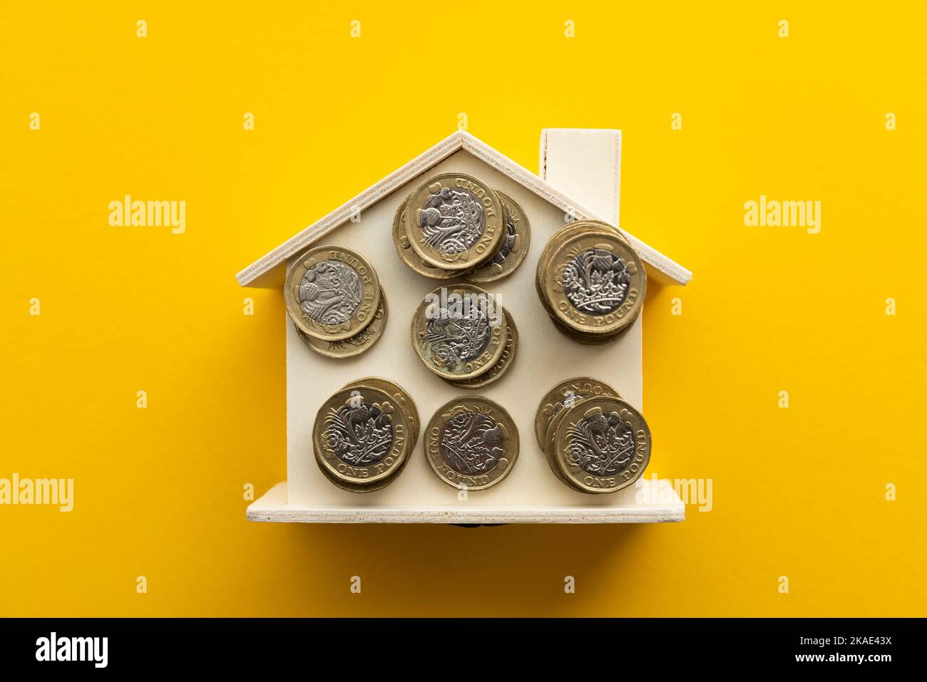 Cost of living background. United Kingdom pound coins on a wooden house Stock Photo