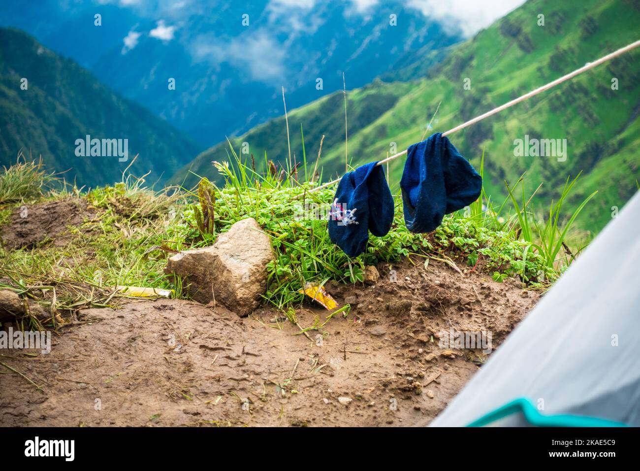 July 14th 2022, Himachal Pradesh India. Pair of trekking socks drying on a wire after a long day trek with landscapes and sky in the background. Stock Photo