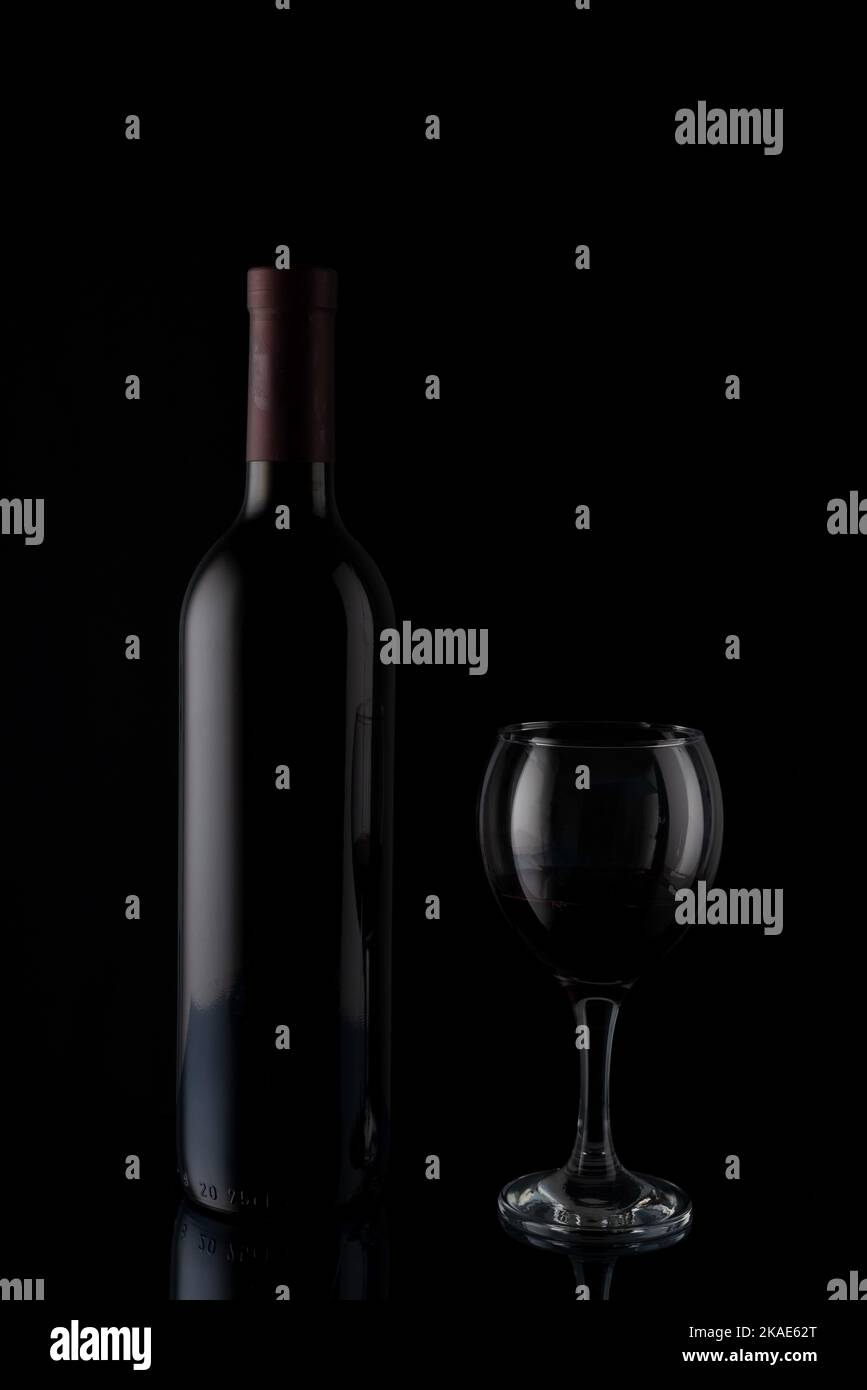 red wine bottle with glass on black mirror background Stock Photo