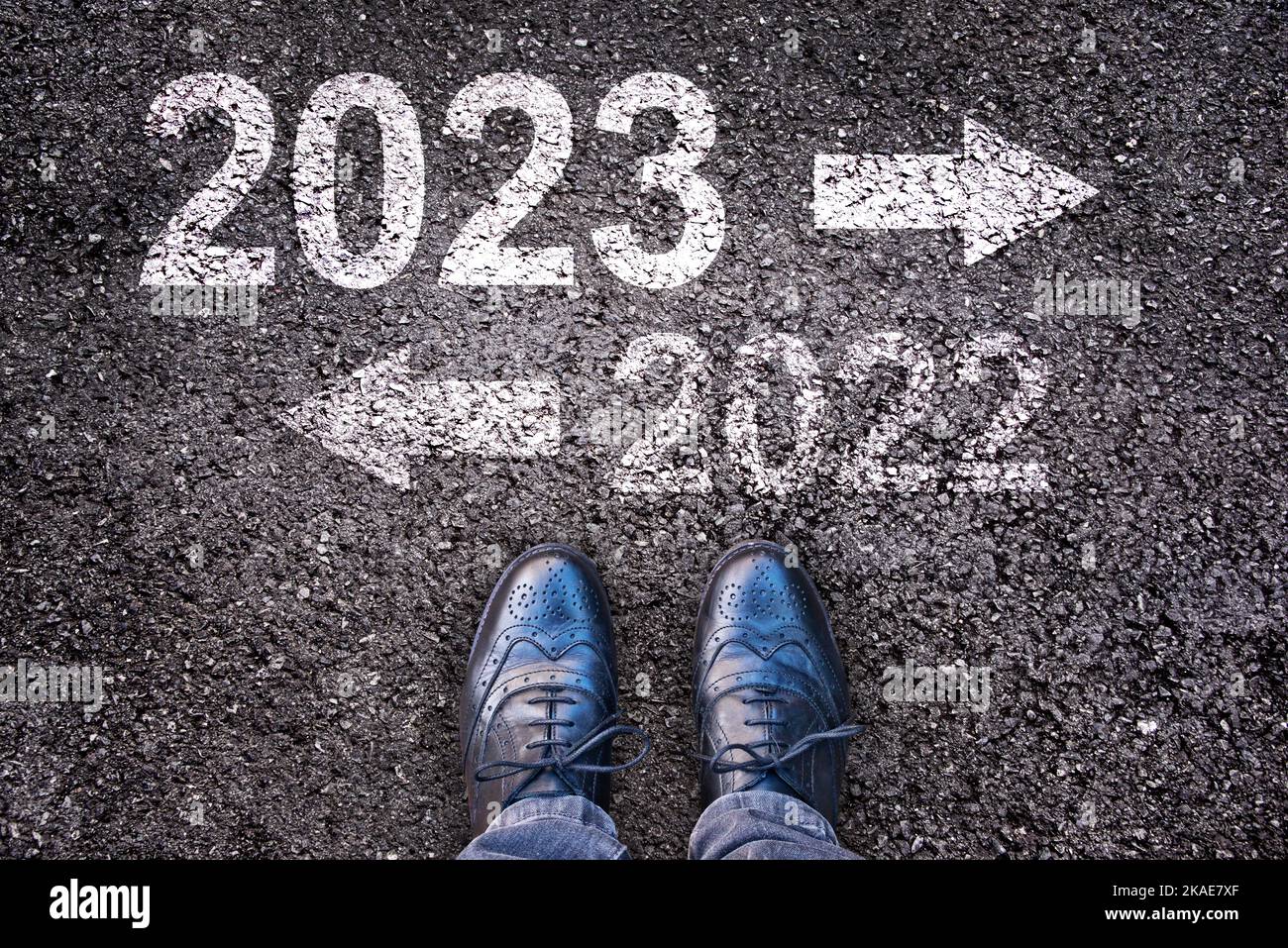 Direction 2023 written on asphalt road background with legs, new year business concept Stock Photo