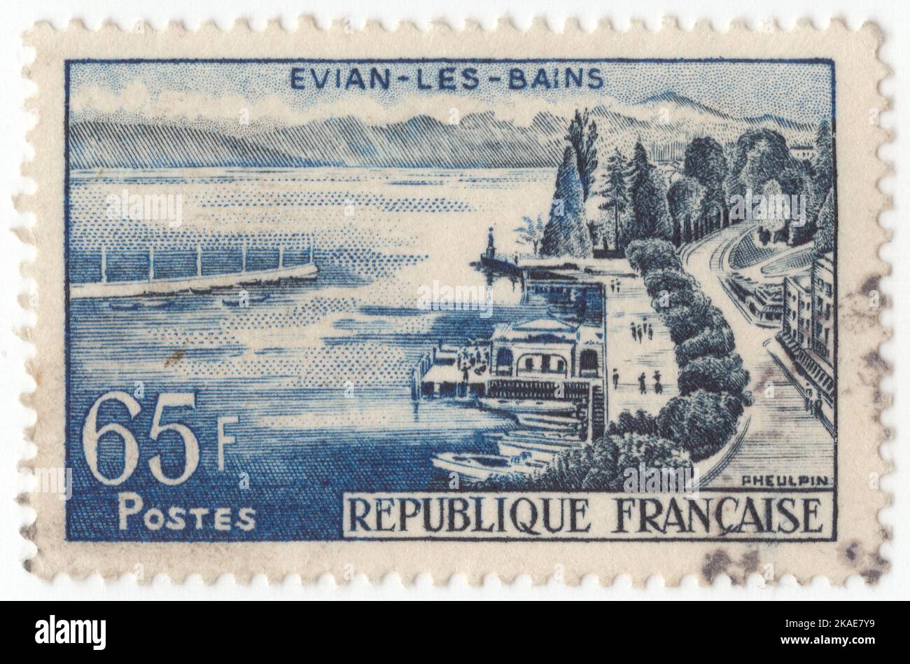 FRANCE - 1957 October 19: An 65 francs dark blue and indigo postage stamp depicting Evian-les-Bains, or simply Evian. A high-market holiday resort and spa town on the shores of Lake Geneva, it has been visited, over two centuries, by royalty such as Kings Edward VII and George V of the United Kingdom and King Farouk of Egypt, and celebrities such as countess Anna de Noailles and Marcel Proust Stock Photo