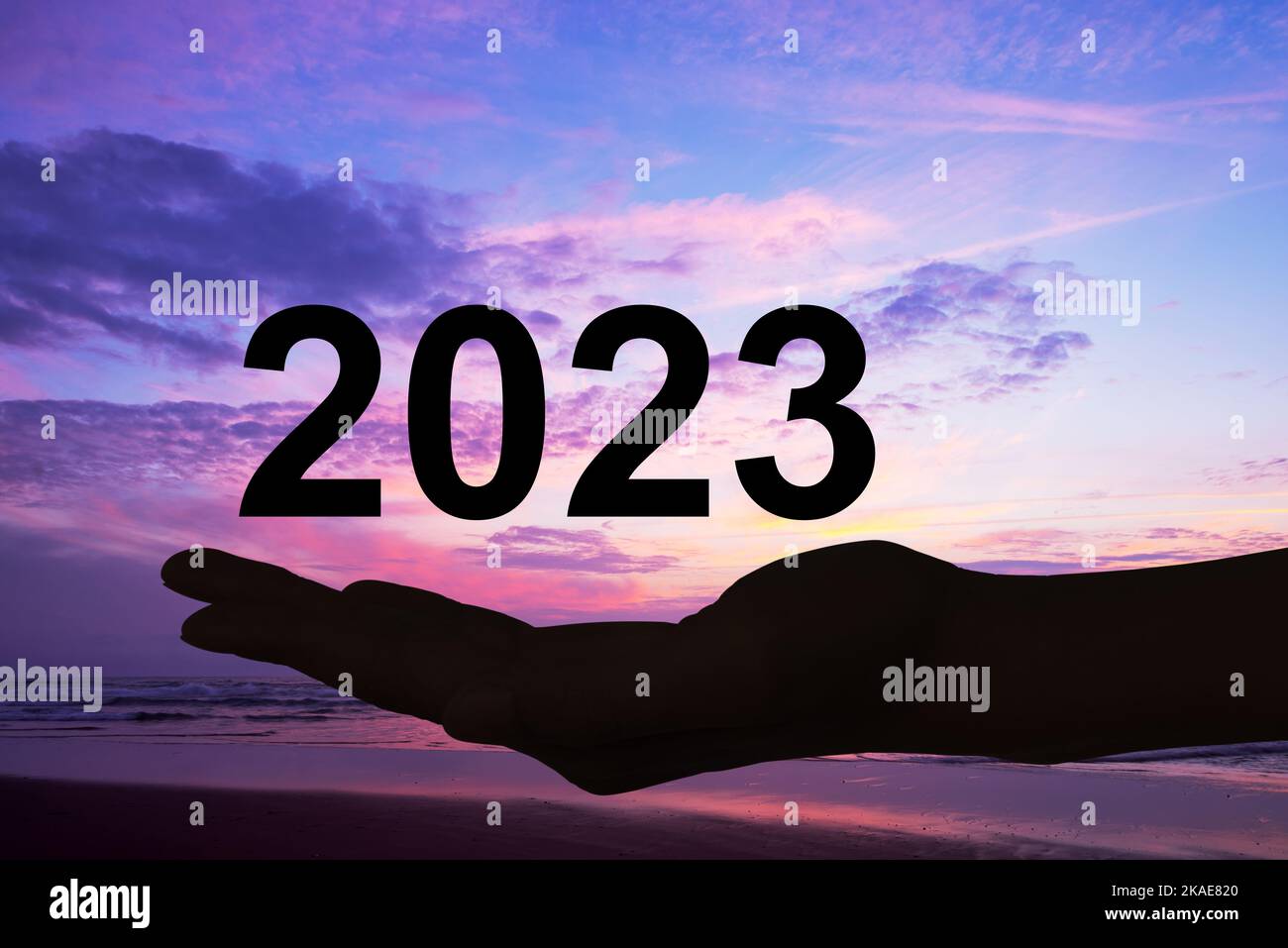 Hand offering 2023 numbers, sunset background, new year card Stock Photo