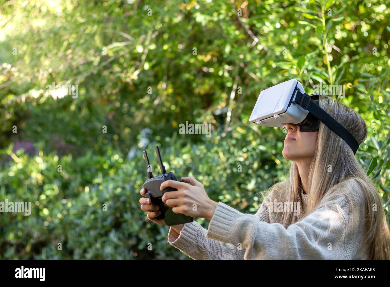 Close up side view of young blond woman controlling a flying drone