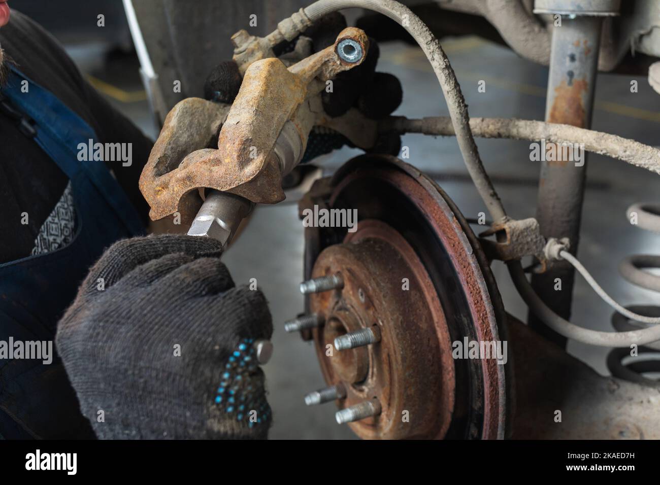 Auto mechanic repairs brake caliper, tightens screw Stock Photo