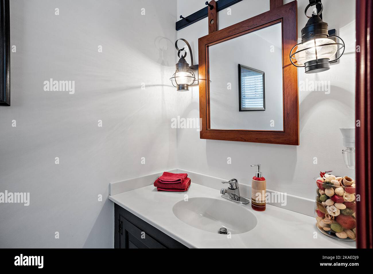 A nicely furnished bathroom with a square mirror and bathroom lighting