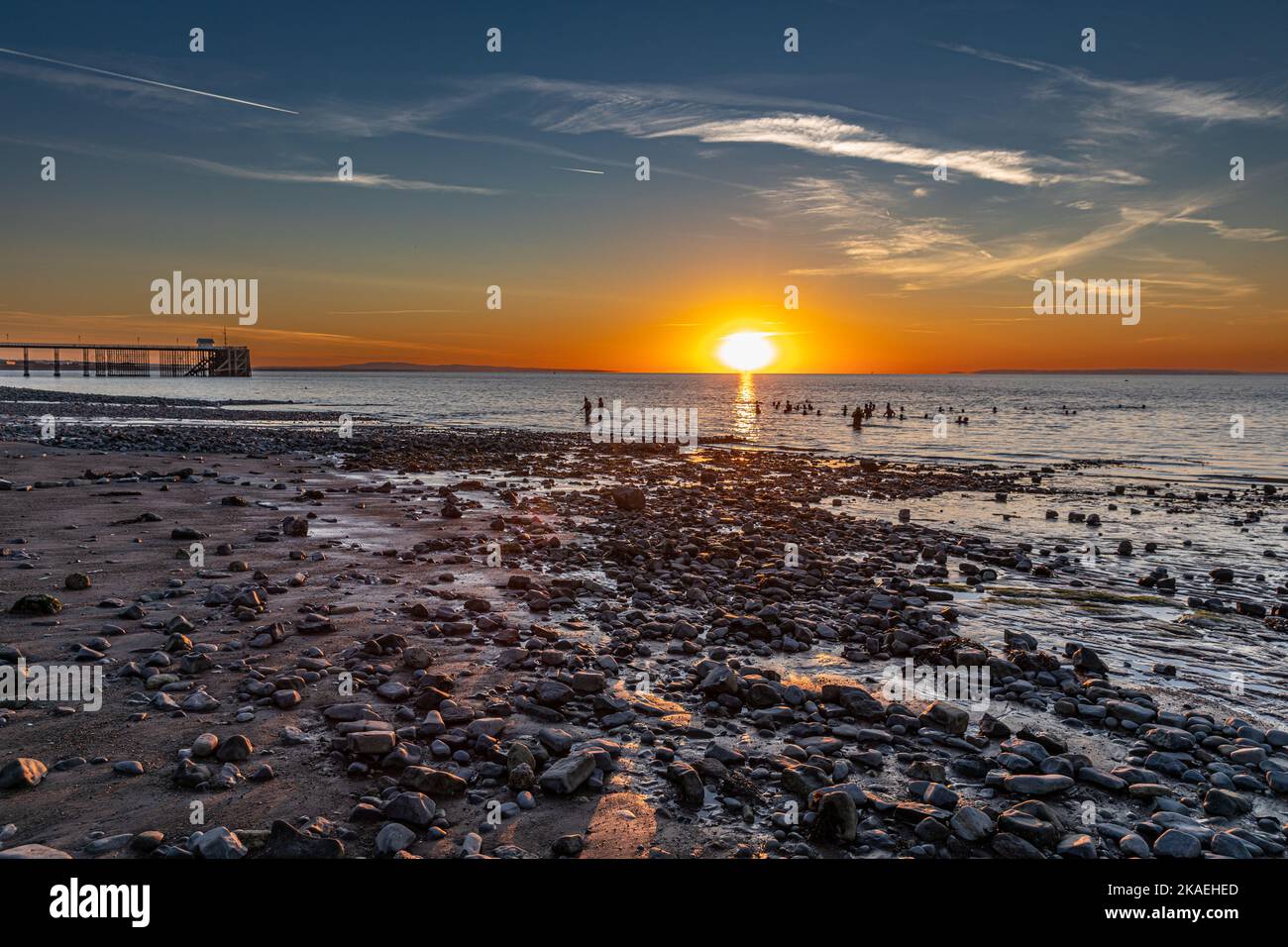 Bathers in the sea at Penarth beach at sunrise on a summers morning. Stock Photo