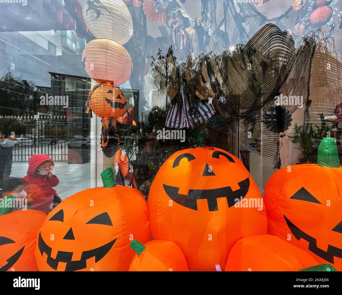 Kids look at the Halloween decorations displayed in a store window in