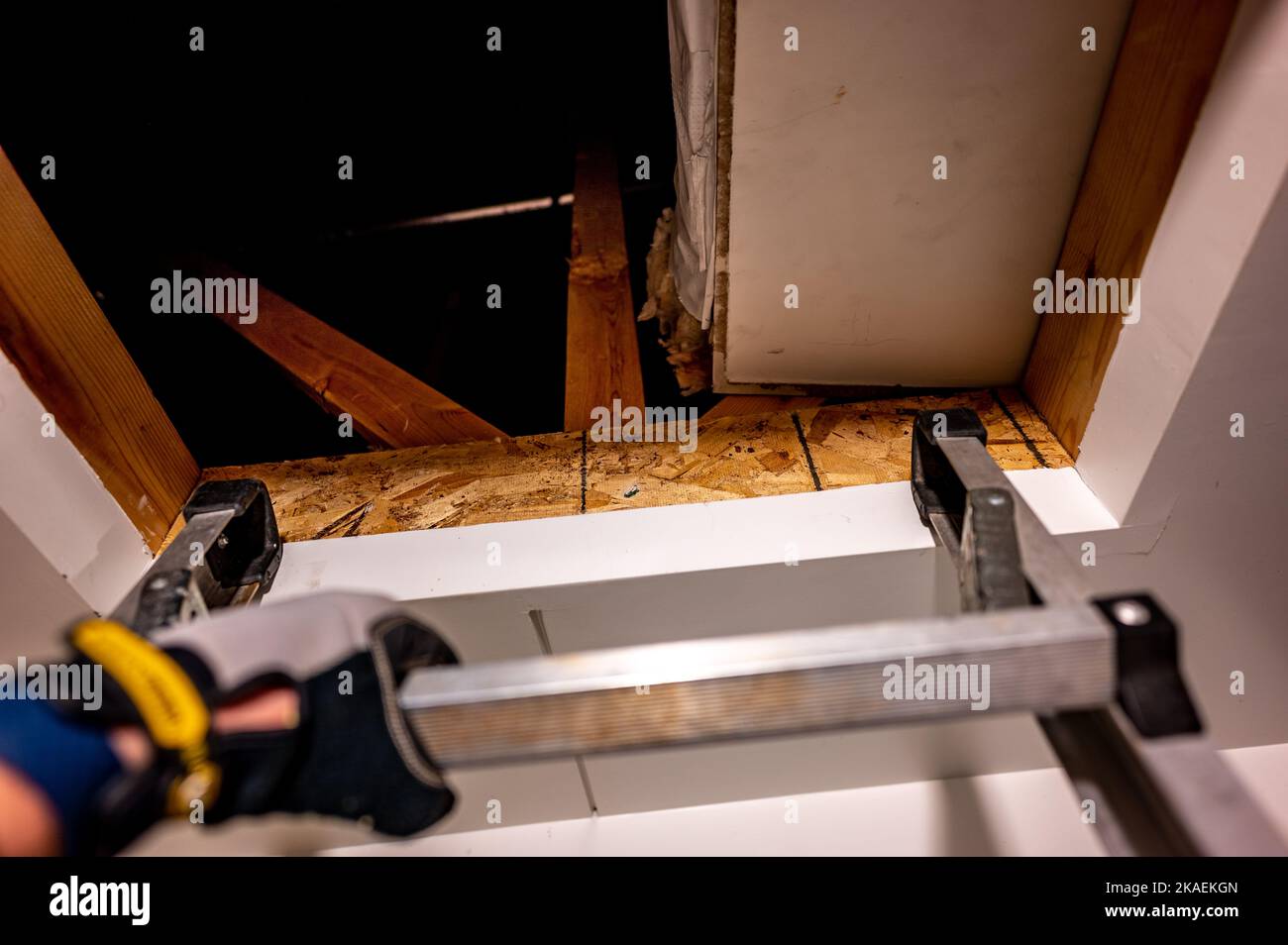 hand gripping the last rung on a ladder leading to an open attic Stock