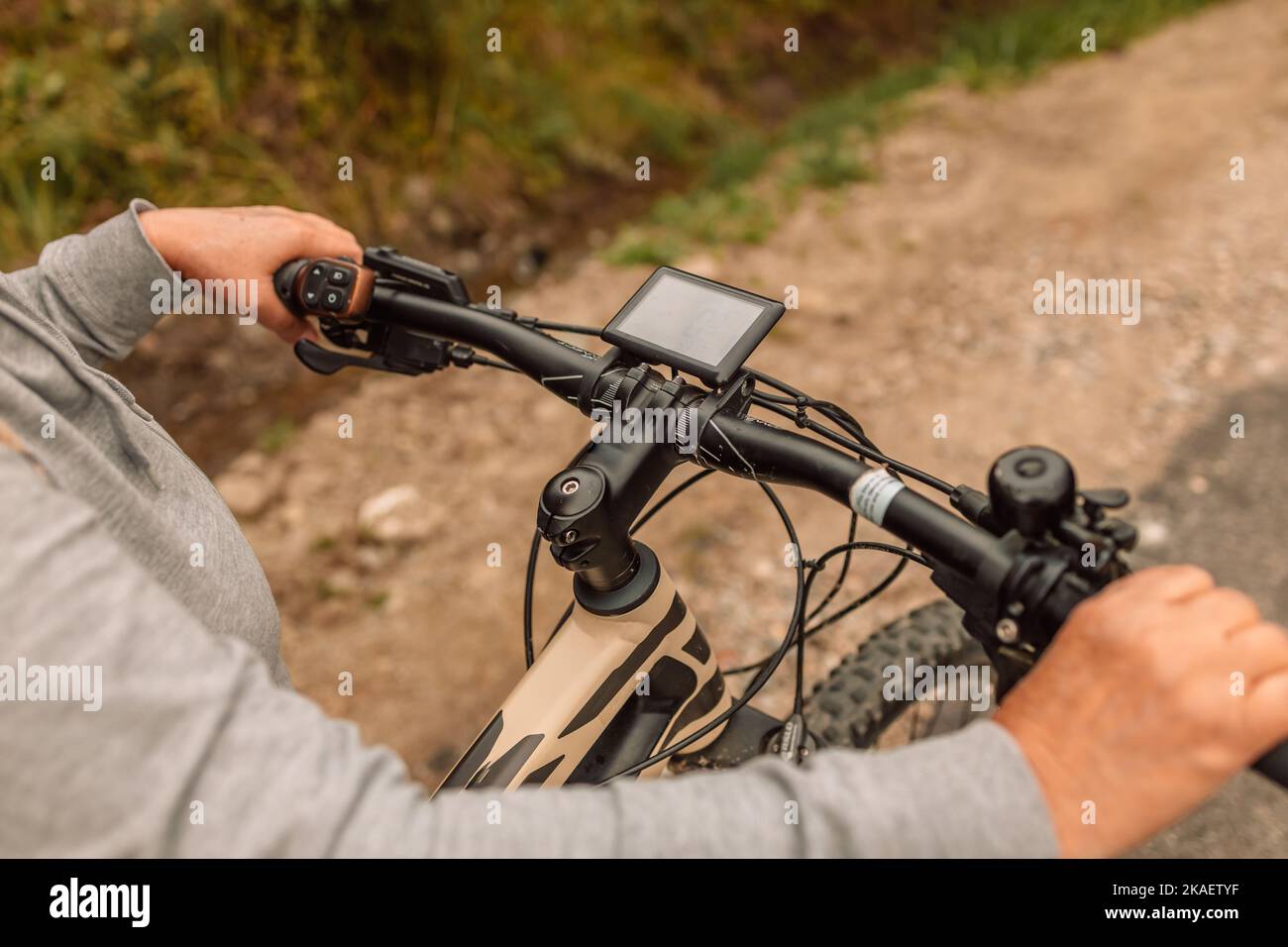 Woman hands with electric bike handlebar driving on an asphalt road in nature Stock Photo