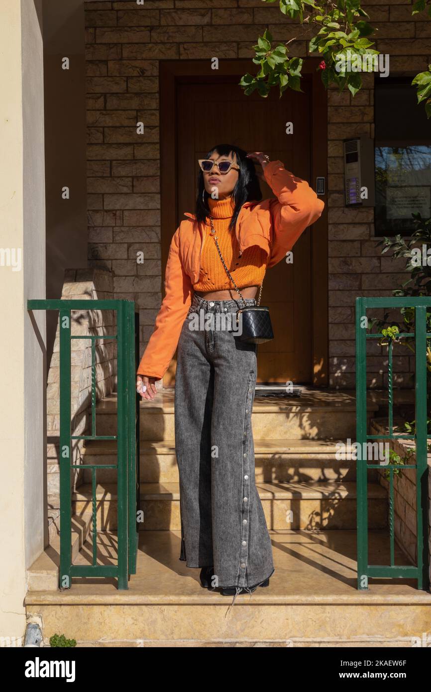 A vertical shot of African woman standing on a porch wearing fashionable clothes Stock Photo