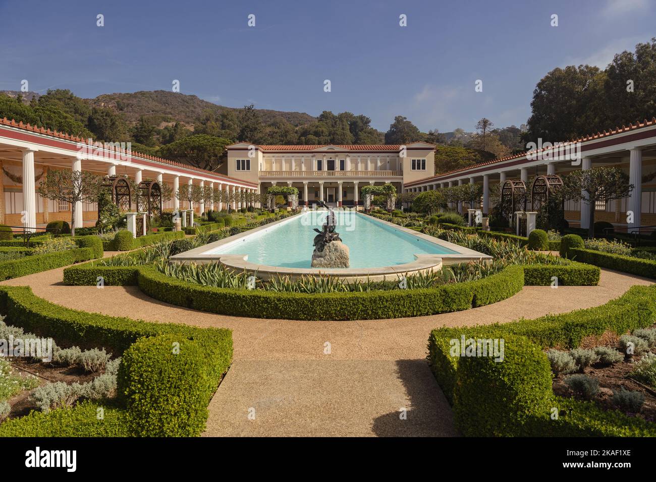 A scenic view of J. Paul Getty Villa Garden with a pool and decorative plants under the blue sky Stock Photo