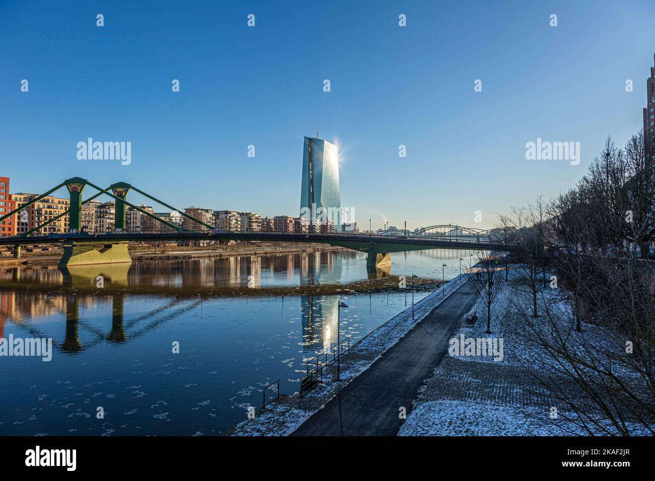 View over river Main in Frankfurt with Flößerbrücke and European Central Bank building with sun reflection in the facade during winter Stock Photo