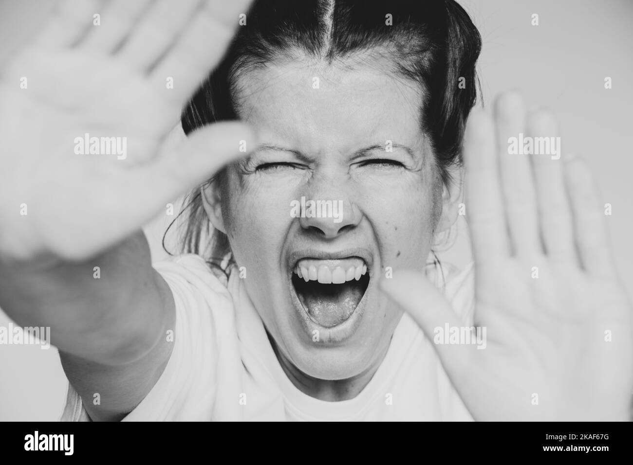 The girl screams and covers her face with her hands isolated background close-up, evil and screaming, stop Stock Photo