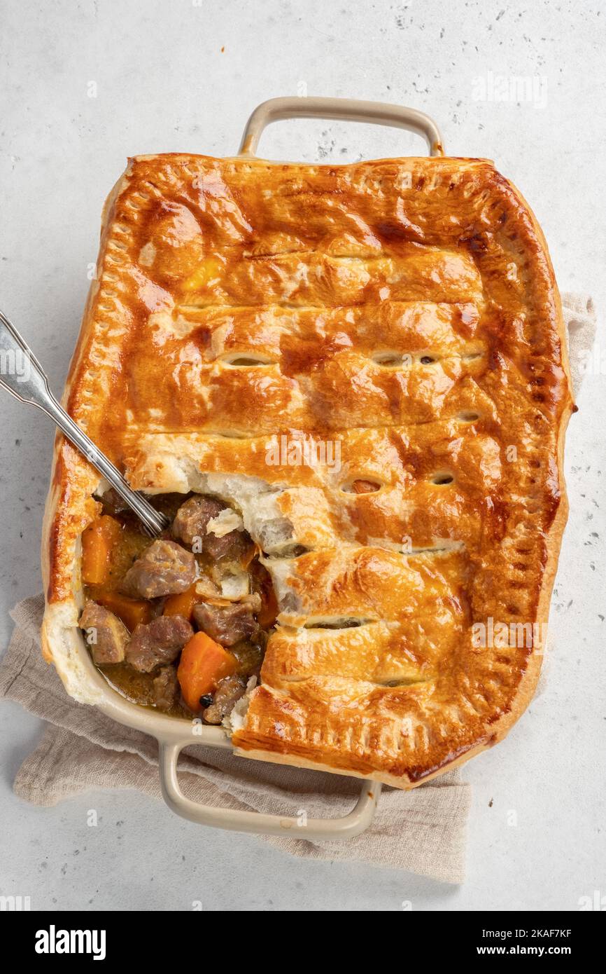 English beef steak pie with crispy puff pastry closeup in a baking