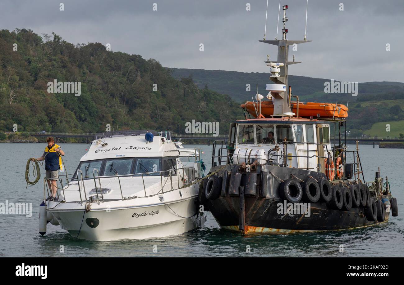 Tug boat with sinking Motor Cruiser or Cabin Cruiser Stock Photo