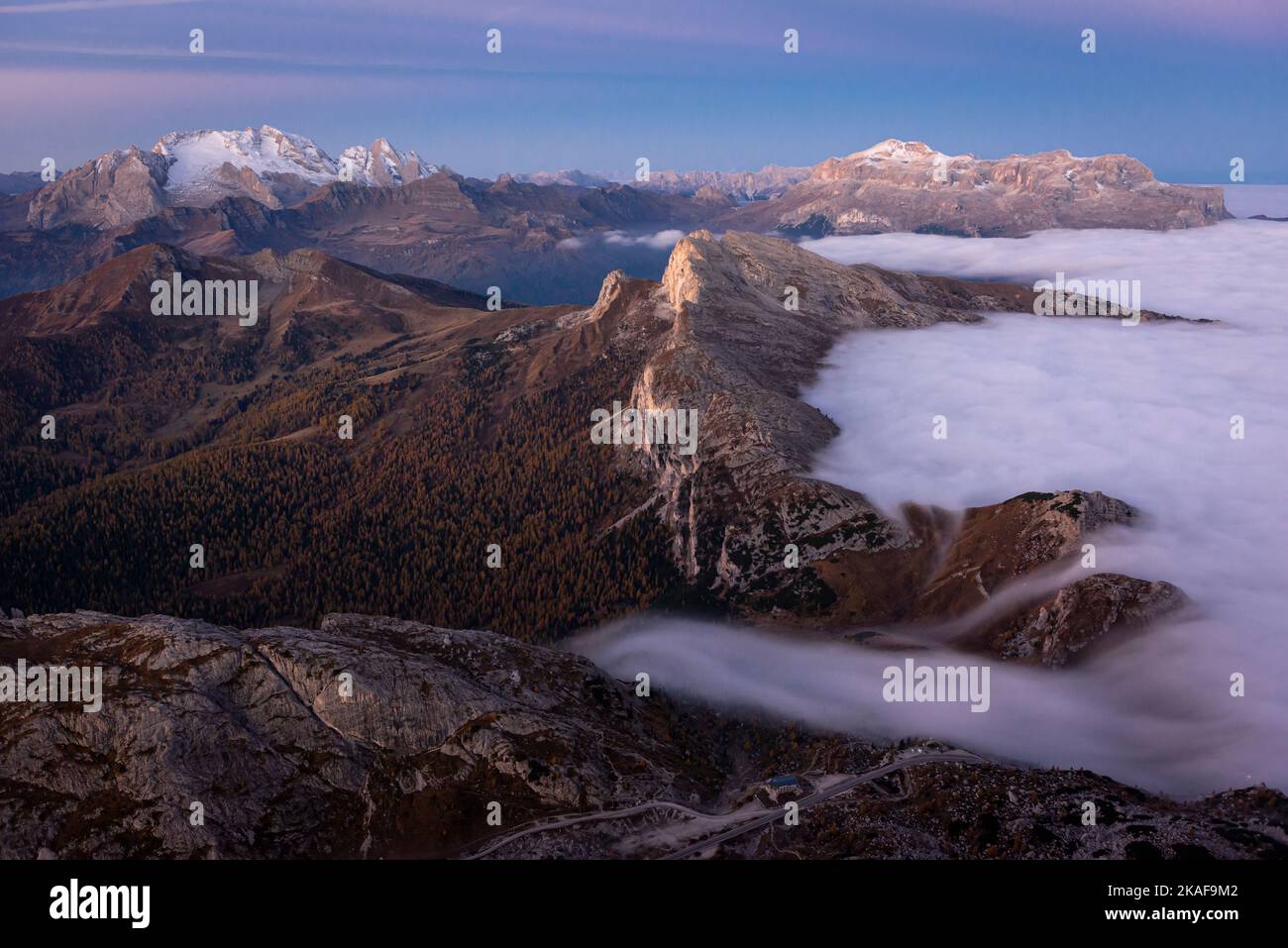 Cold air fog flowing over the Valparola Pass in front of the Settsass and the Sella massif at dawn, Dolomites, Italy Stock Photo