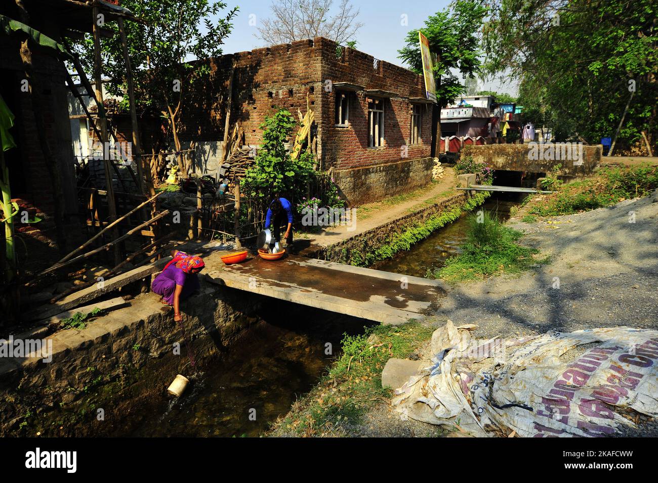 Indian woman collecting water at the Boar canal, built by Sir Henry Ramsay in 1860 at Kaladhungi, Uttarakhand, India Stock Photo