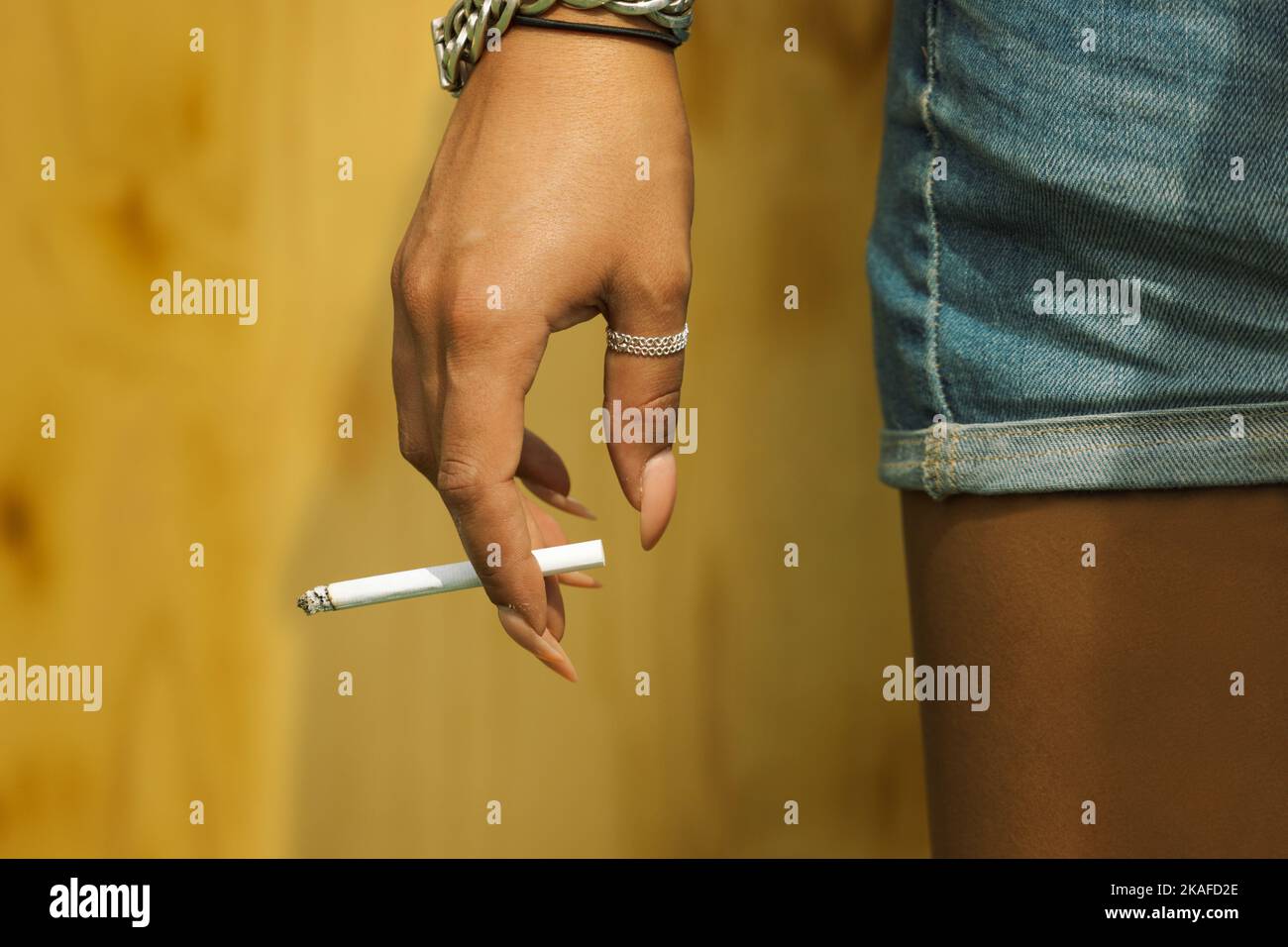woman in shorts and sculptured nails holding cigarette Stock Photo