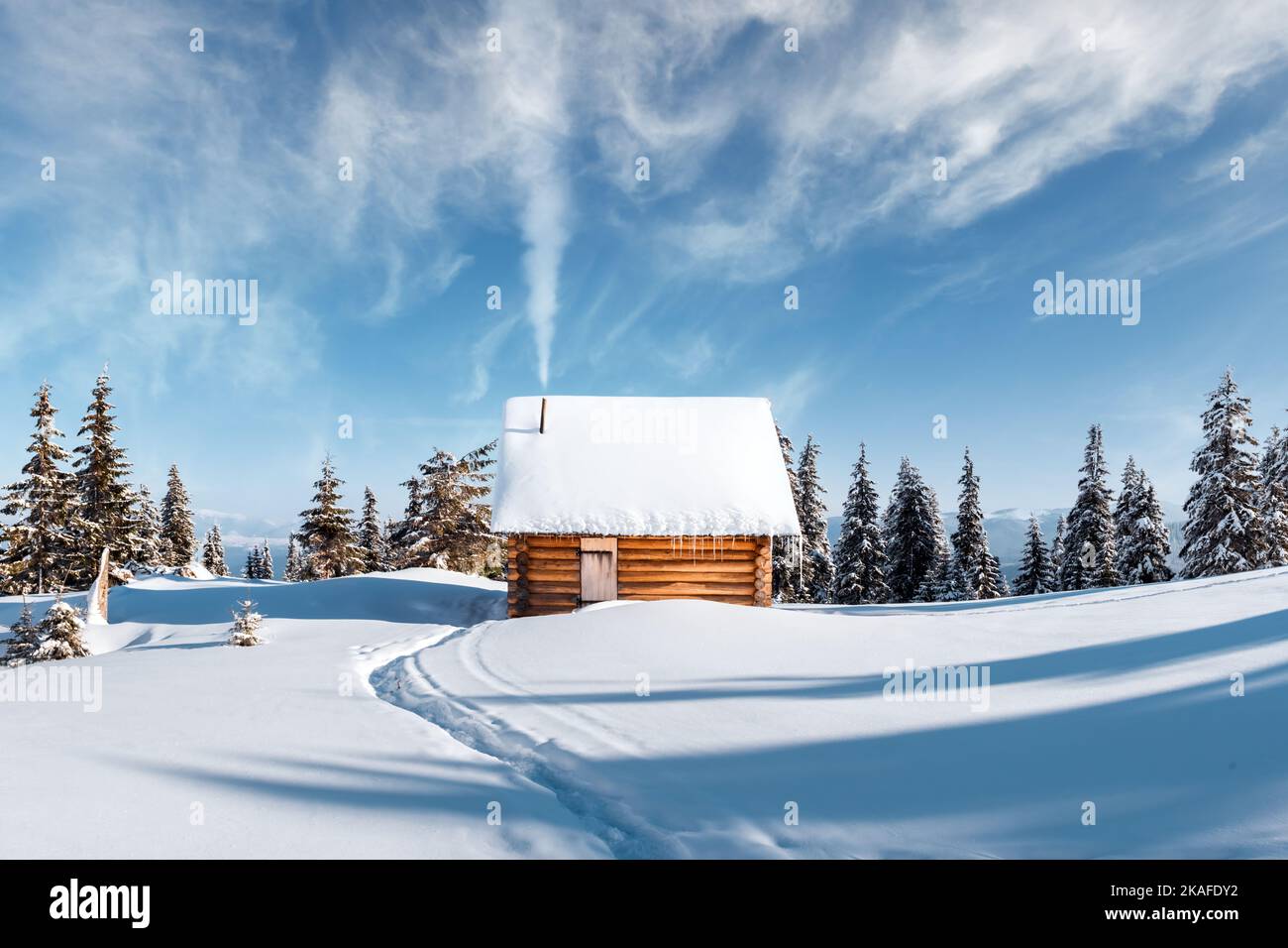 Fantastic winter landscape with wooden house and smoke from chimney in snowy mountains. Christmas holiday concept. Carpathians mountain, Ukraine, Europe Stock Photo